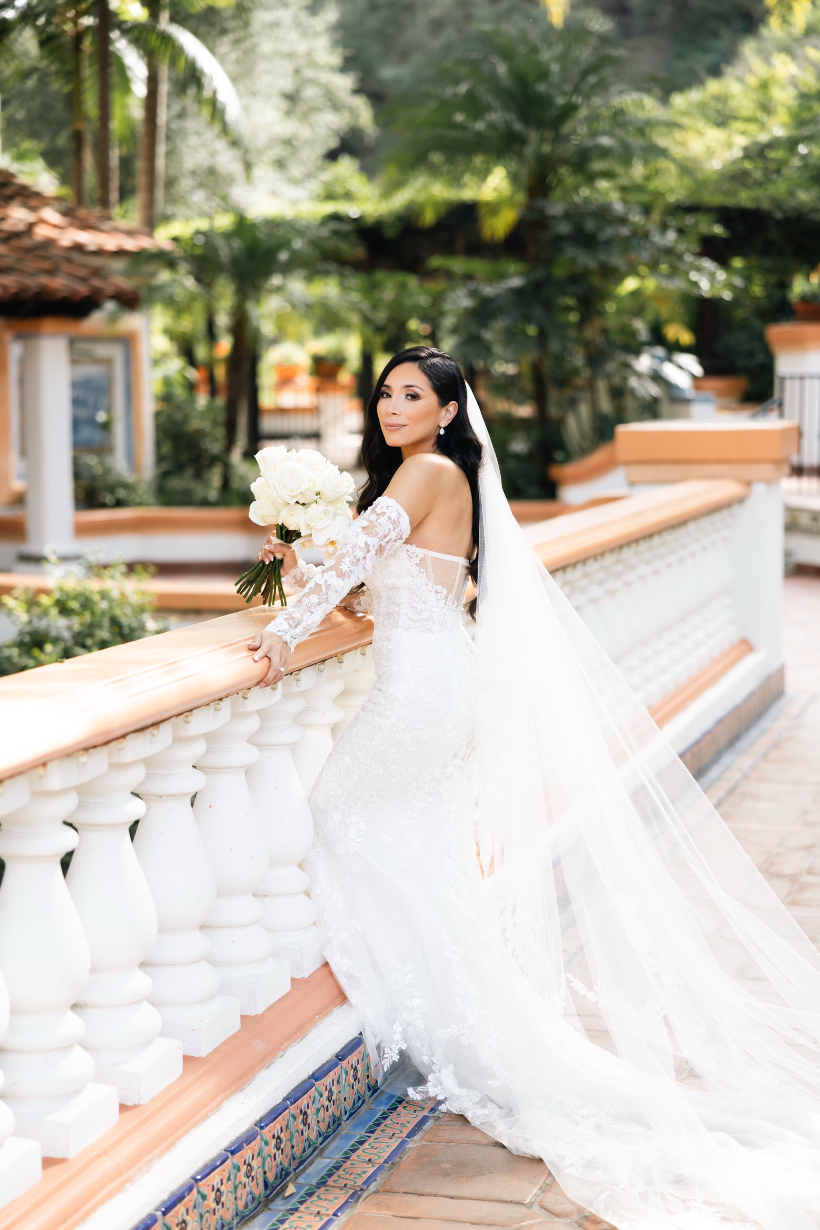Michelle looking over her shoulder with bouquet and veil on bridge at Rancho Las Lomas