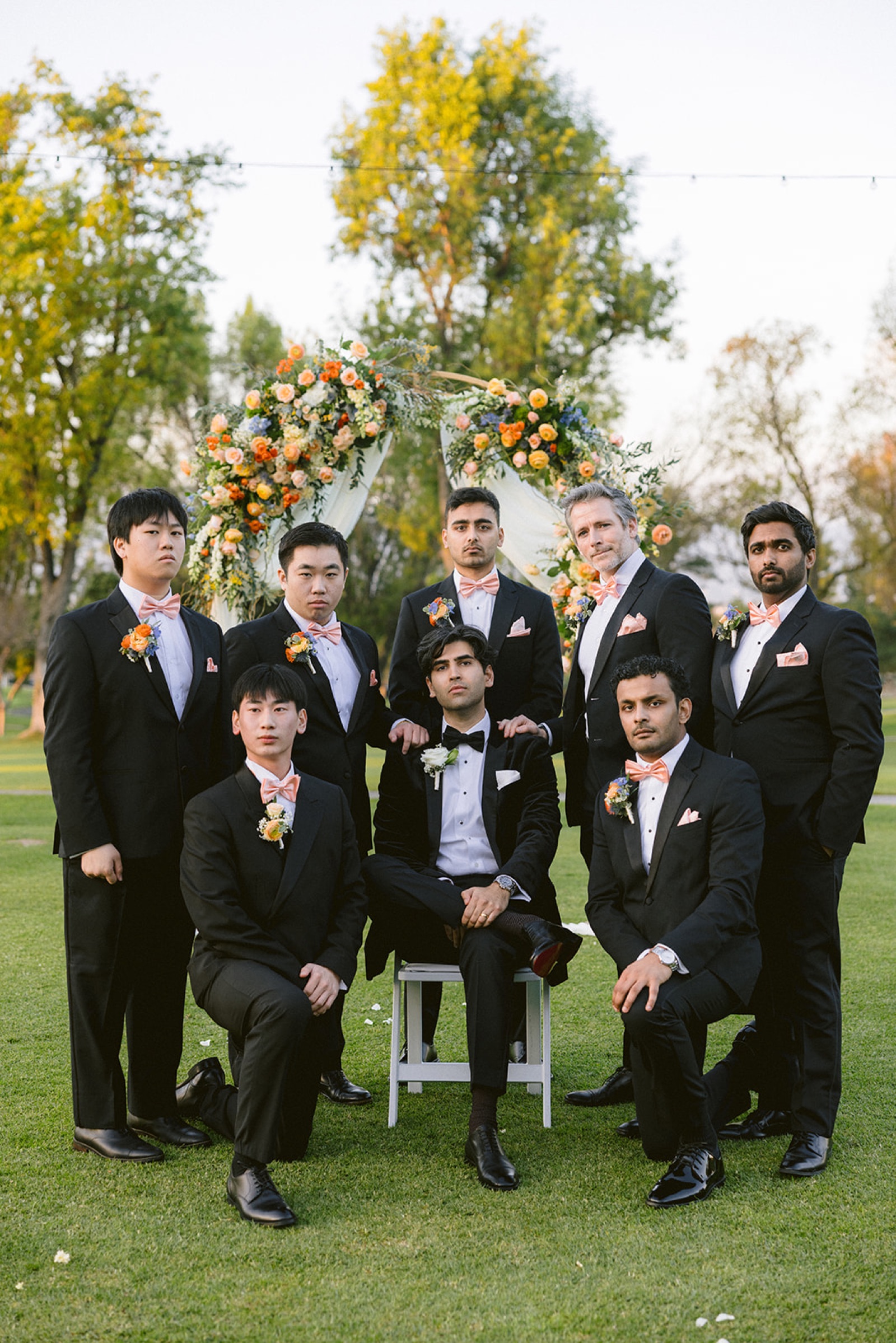 Full groomsmen group photo at the ceremony arch