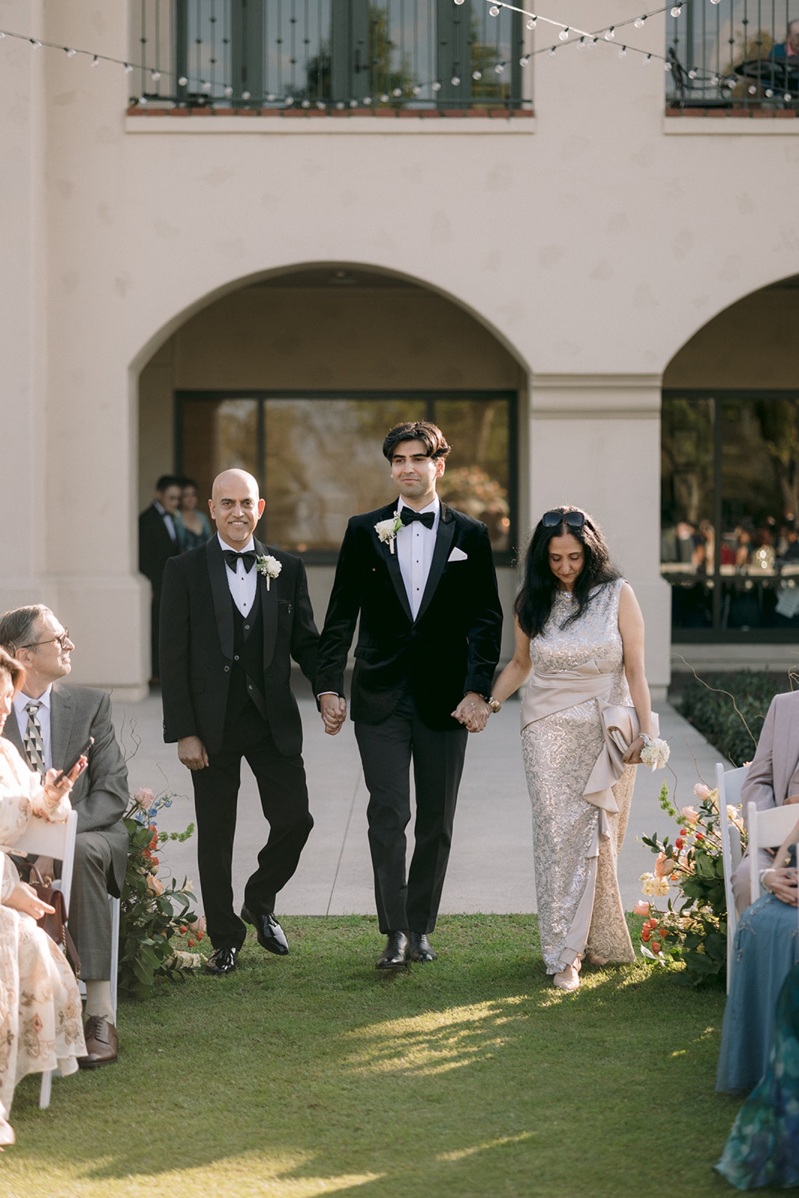 Groom walking down the aisle with his parents